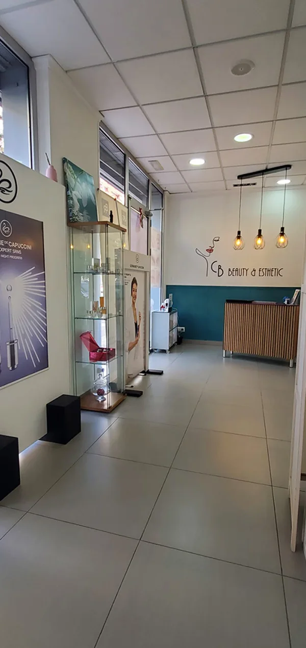 Recepción de CB Beauty & Esthetic, con el logo del centro en la pared y el mostrador de madera sobre panel verde petróleo